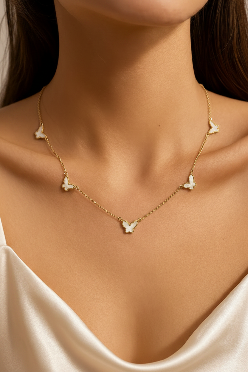 Gold necklace with six pearl butterfly pendants on a person wearing a white top.